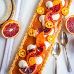Blood Orange Curd Tart on top of a piece of linen with fresh cut oranges next to the tart