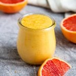 Grapefruit Curd in a Small Jar next to fresh cut grapefruit