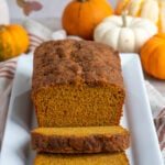 Pumpkin Bread on white platter with mini pumpkins in the background