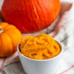 Pumpkin Puree in a small bowl with whole pumpkins in the background