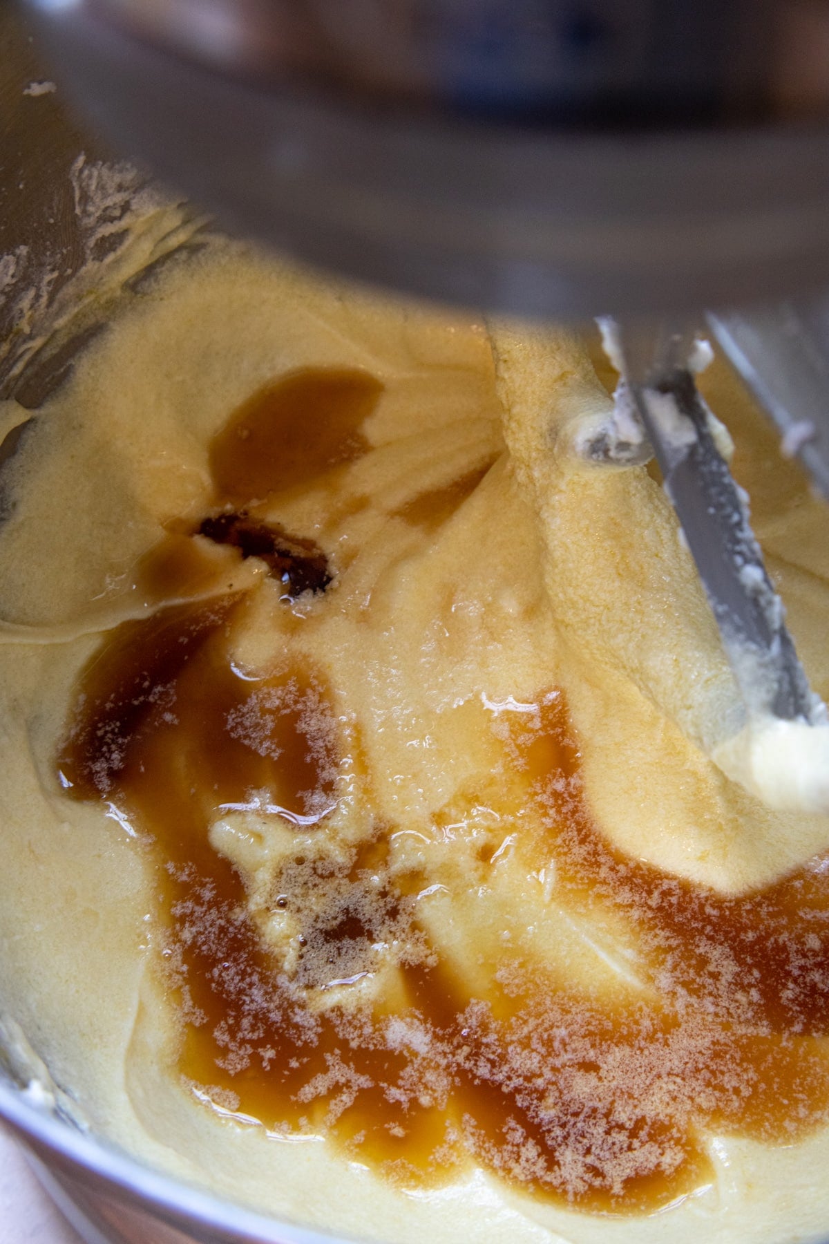 Rum and vanilla added to the cake batter in the bowl of a stand mixer