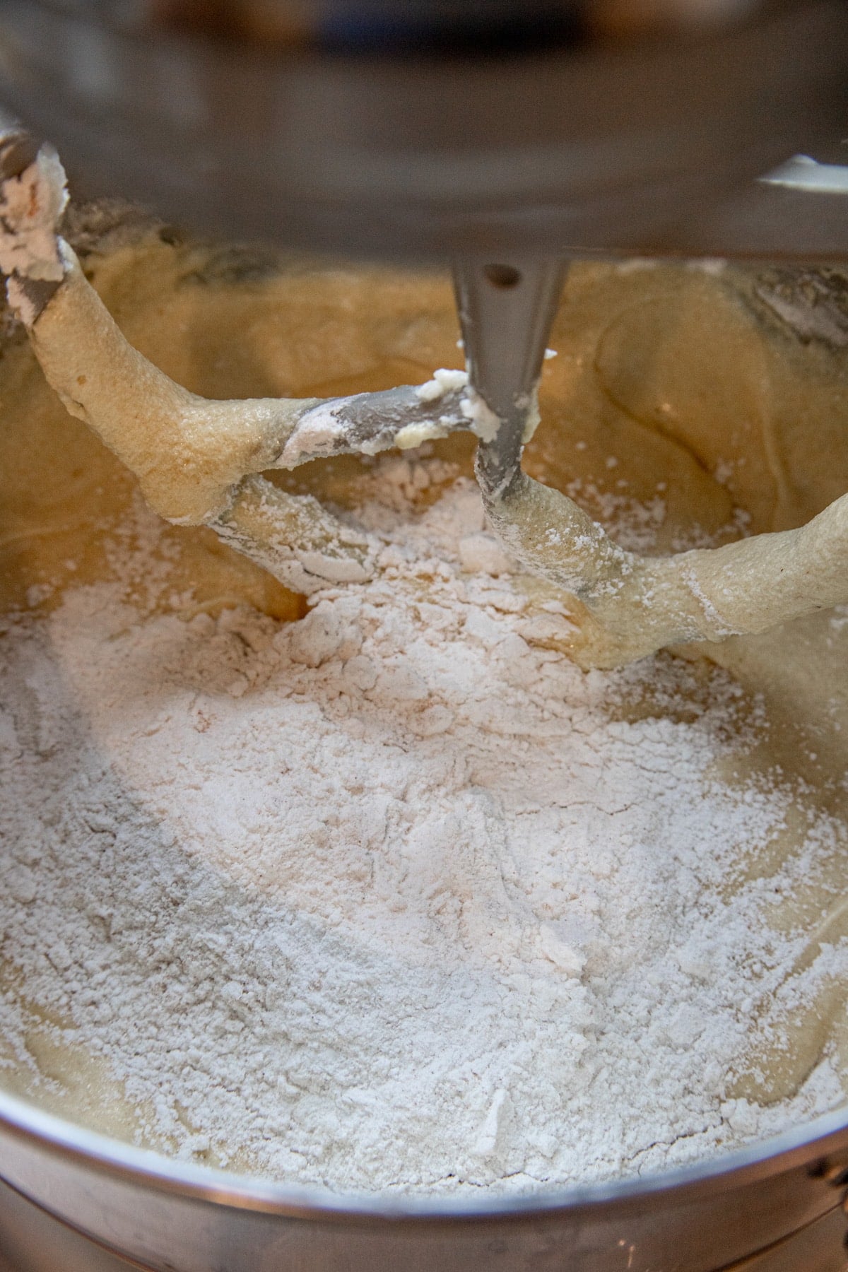 Flour added to the eggnog cake batter in the bowl of a stand mixer