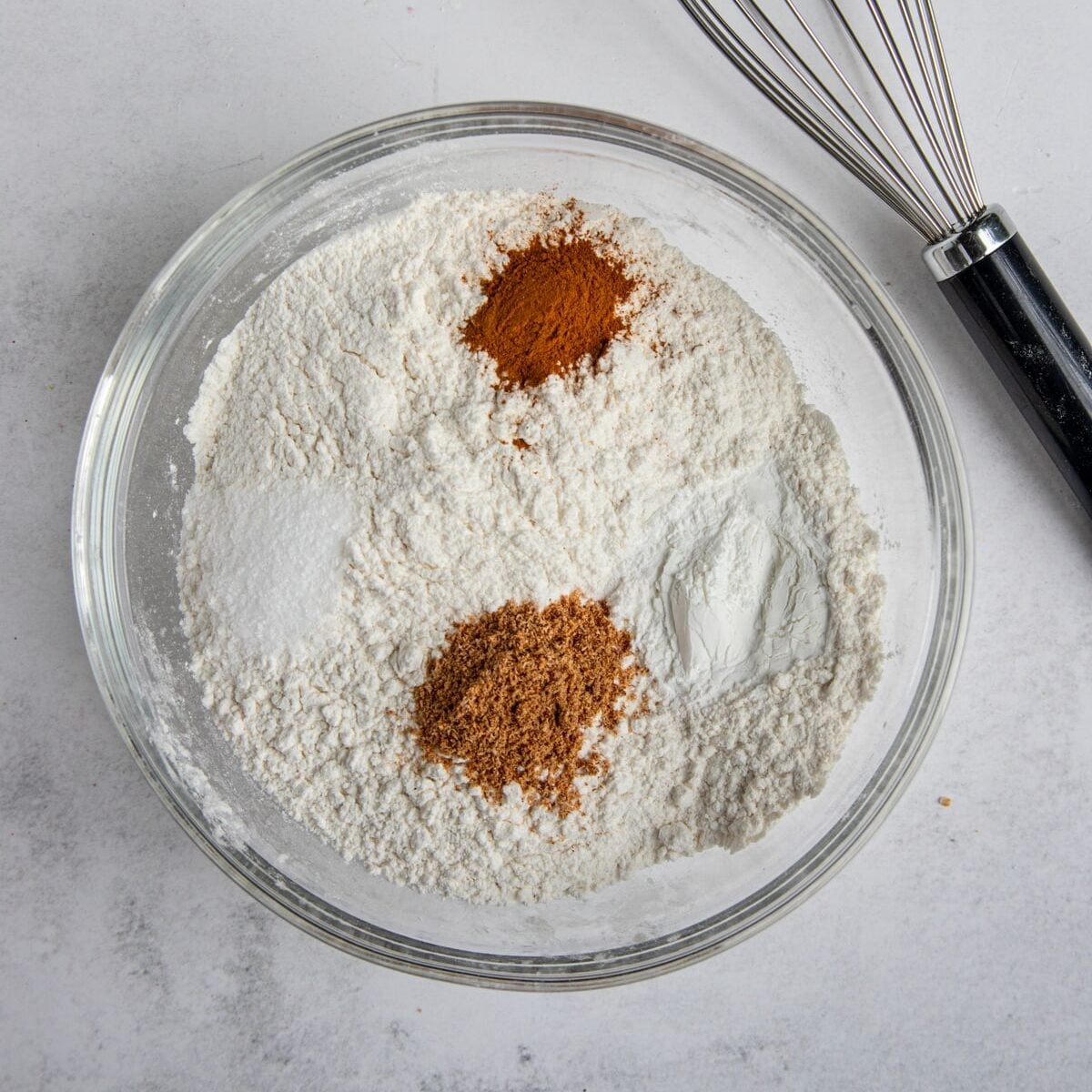 Flour, baking soda, salt, ground cinnamon, ground nutmeg in a glass mixing bowl