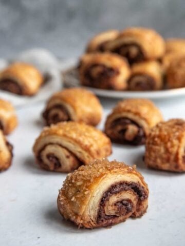 Chocolate Rugelach on a flat surface on a dessert plate in the background