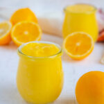 Meyer lemon curd in a small jar surrounded by fresh Meyer lemons