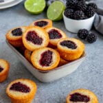 blackberry financiers in a rectangular bowl next to a small bowl of blackberries