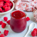 raspberry sauce in a pint jar with a bowl of fresh raspberries in the background
