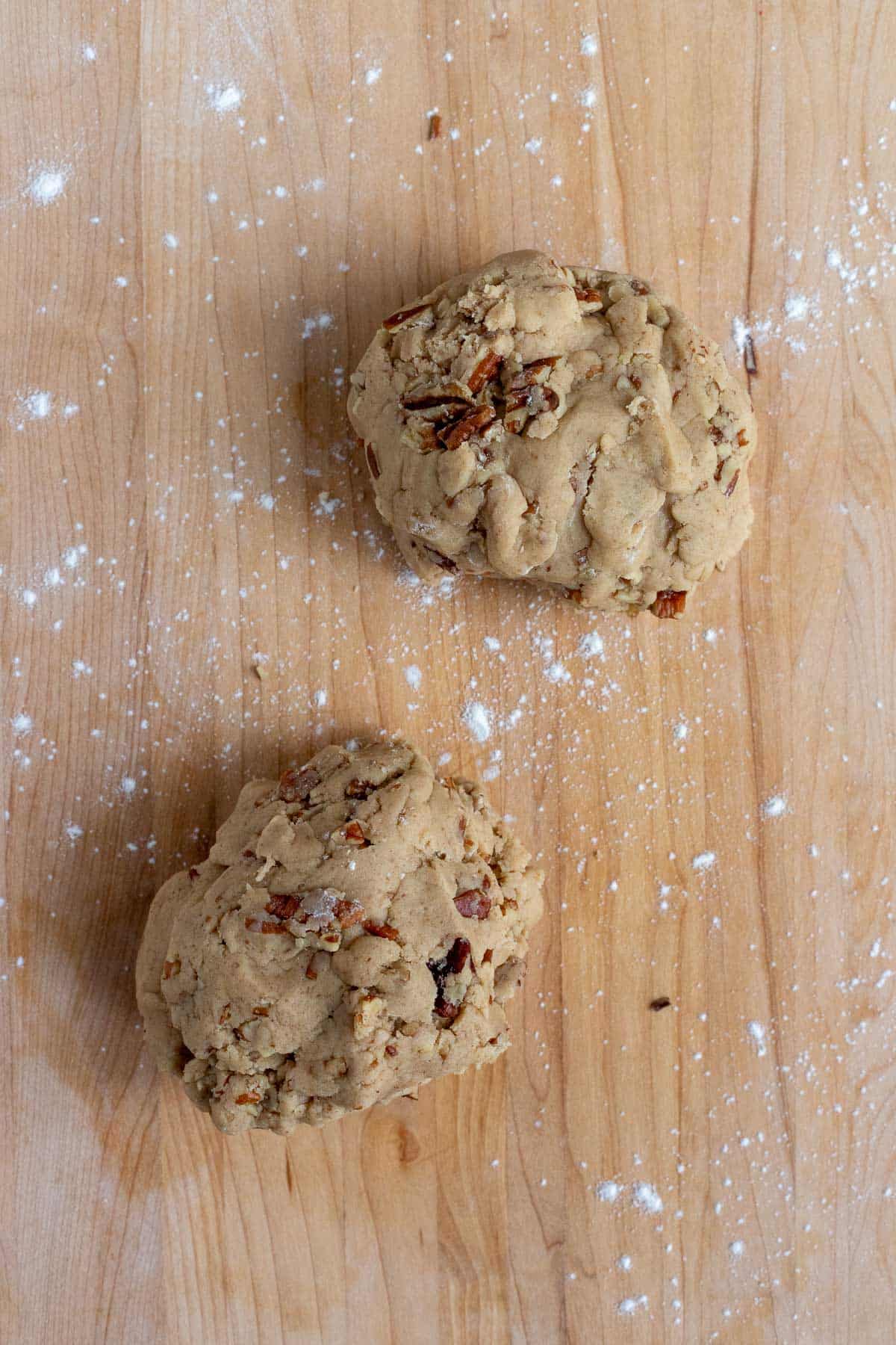 The brown sugar pecan dough divided into two pieces. The dough is on a wooden work surface