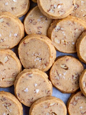 Brown sugar pecan cookies layed out on a flat surface. The cookies are 2-inches round and overlap each other