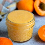 Apricot curd in a small jar with fresh apricots next to the jar