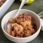 Apple crumble in a white bowl with a spoon in the bowl