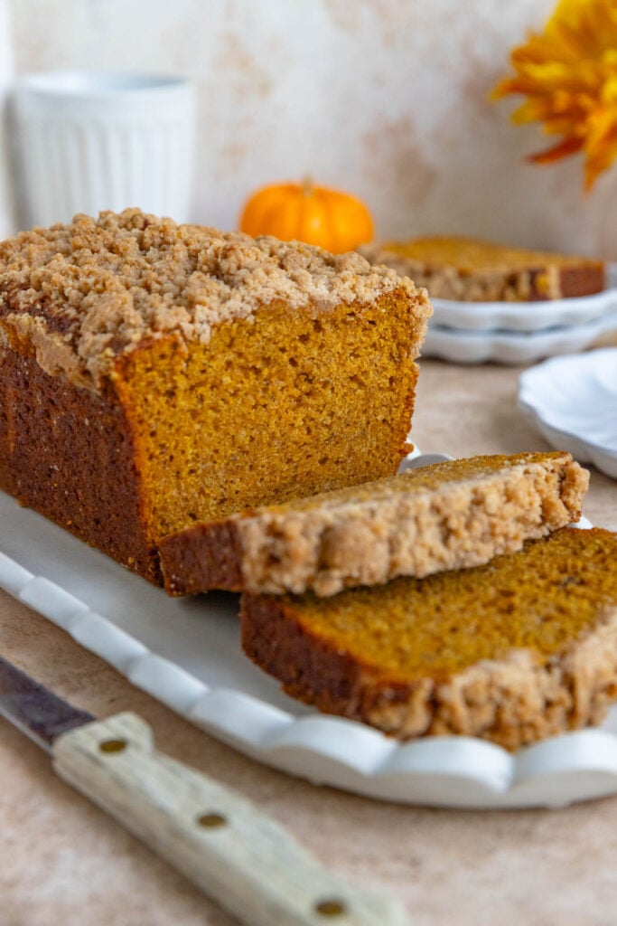 A loaf of banana Pumpkin Bread on a platter with 2 slices laying flat on the platter