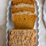 A sliced loaf of banana pumpkin bread on a white ceramic platter