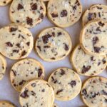 Chocolate hazelnut shortbread cookies laying on a white surface in a single layer.