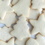 A pile of Christmas cream cheese sugar cookies arranged on a board. The cookies are plain and undecorated