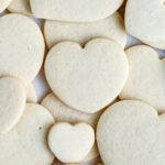 Plain cream cheese sugar cookies of various sizes piled on top of each other on a flat surface