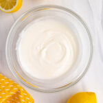 Lemon glaze in a glass bowl with fresh lemons next to the bowl