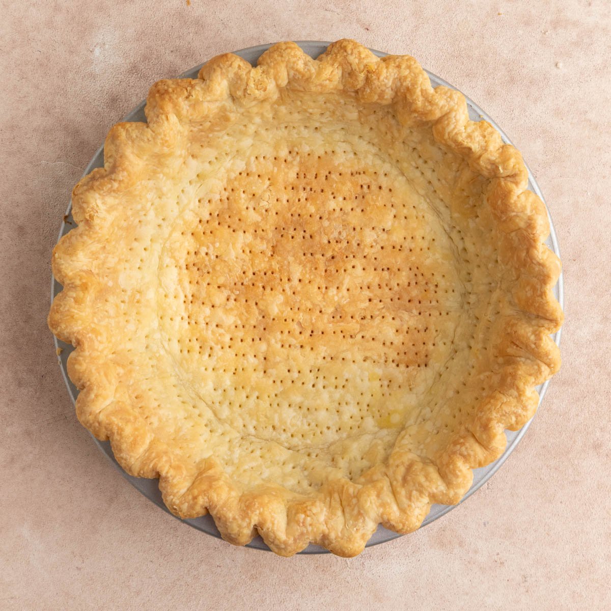 Baked pie crust in a metal pan.  The edges and bottom are golden brown and the edges are slightly puffed