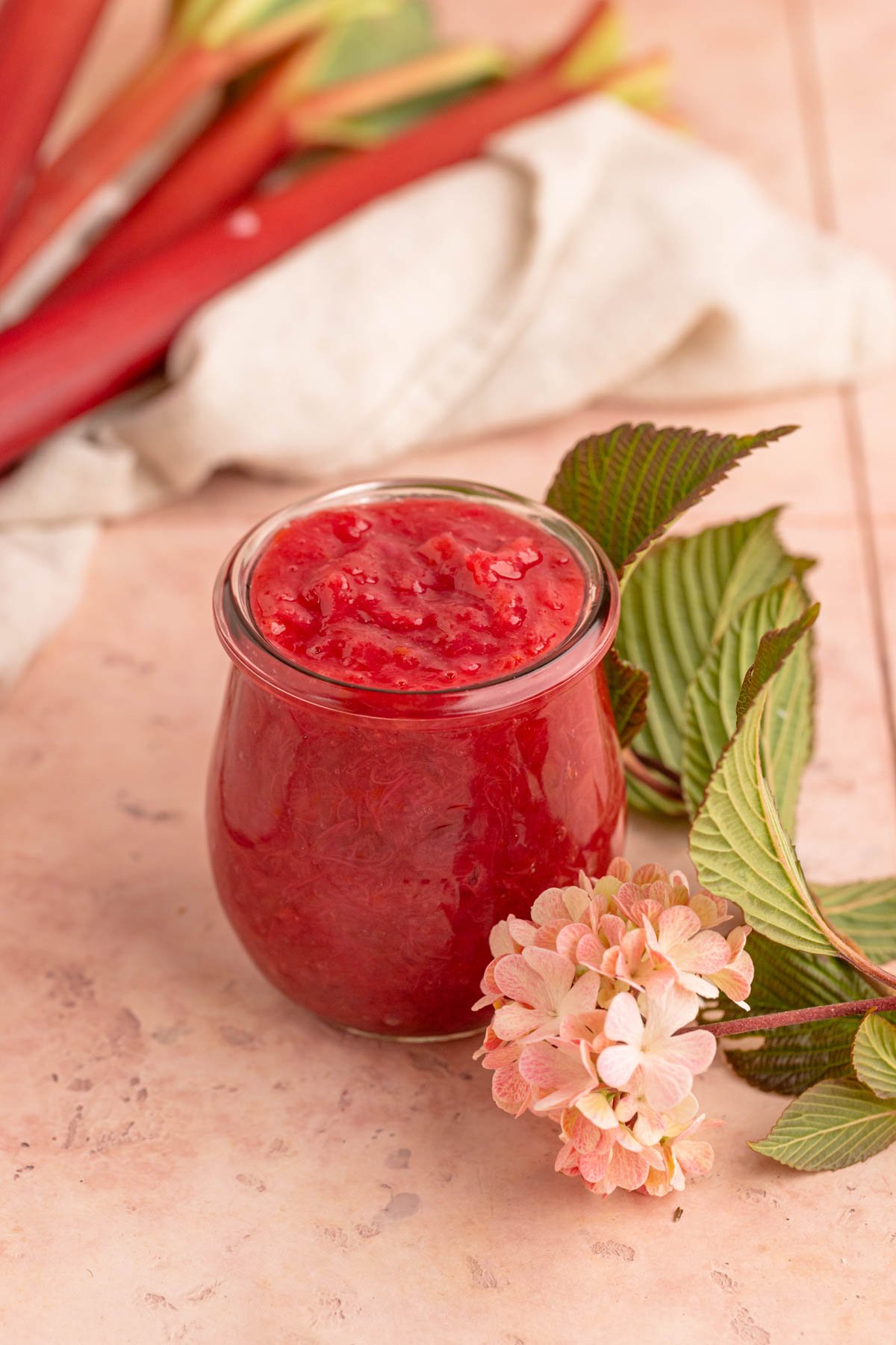 Rhubarb compote in an 8 ounce jar with a flower next the jar