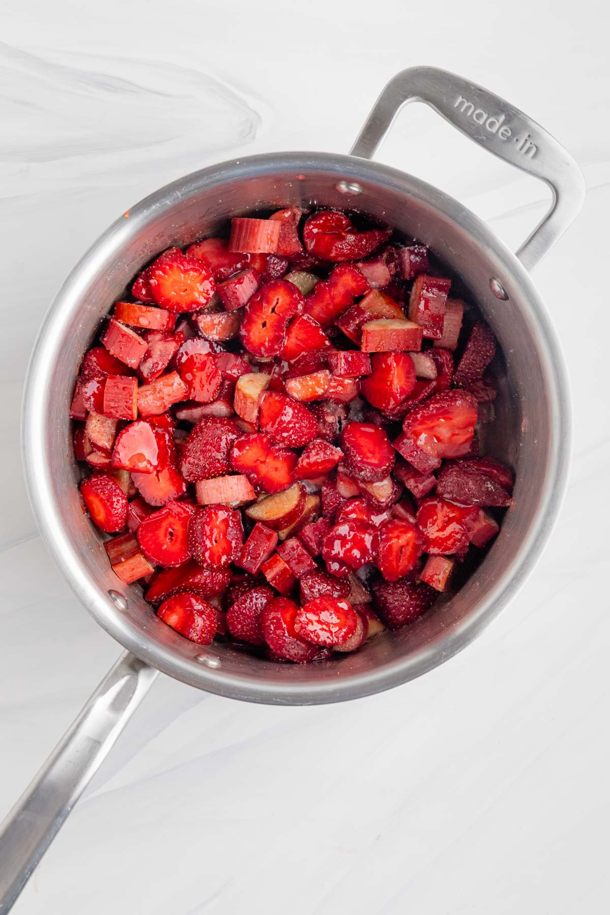 Sliced strawberries and rhubarb combined with sugar and lemon juice in a stainless steel sauce pan