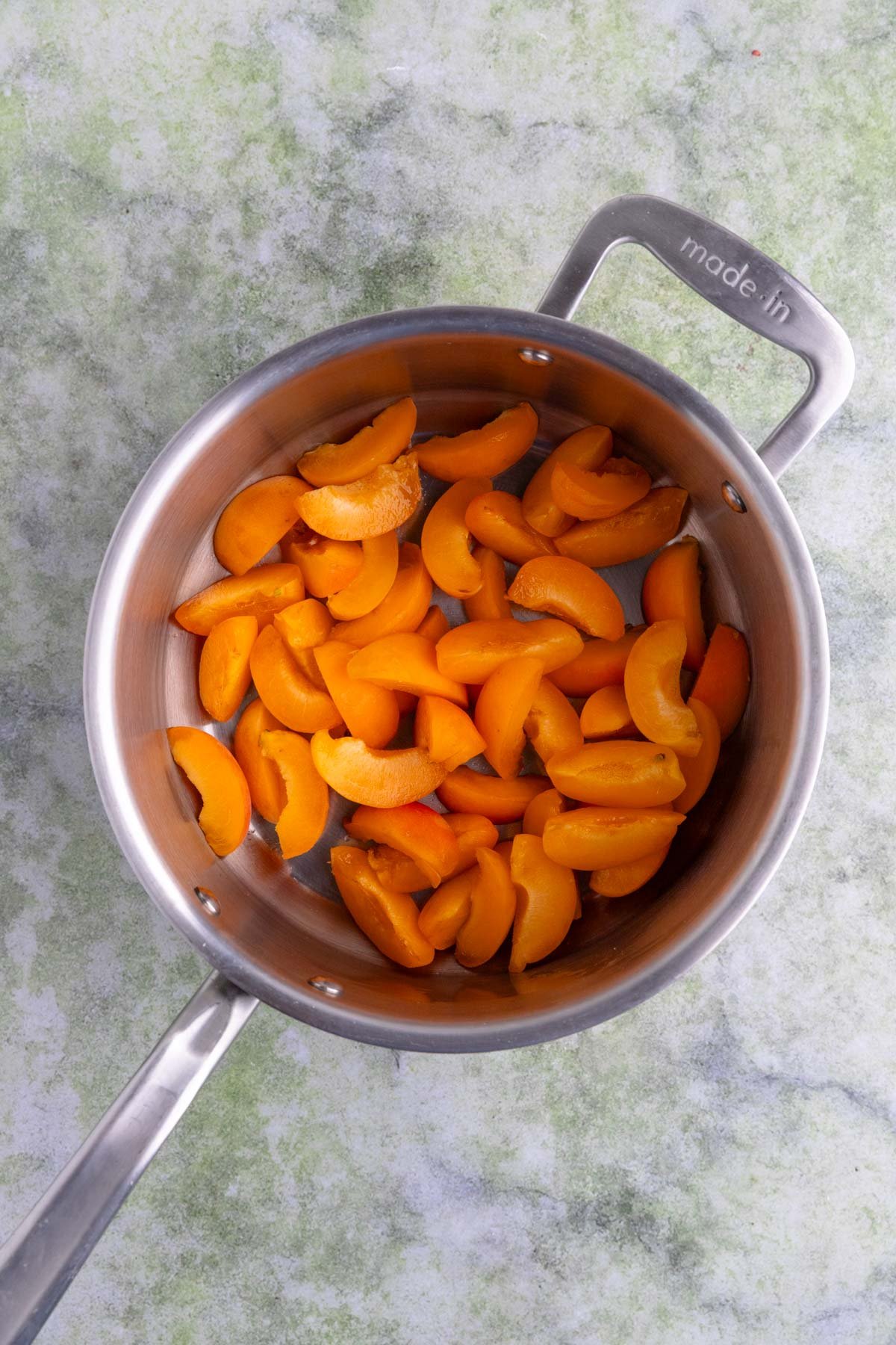 Apricots cut into wedges in a stainless steel saucepan