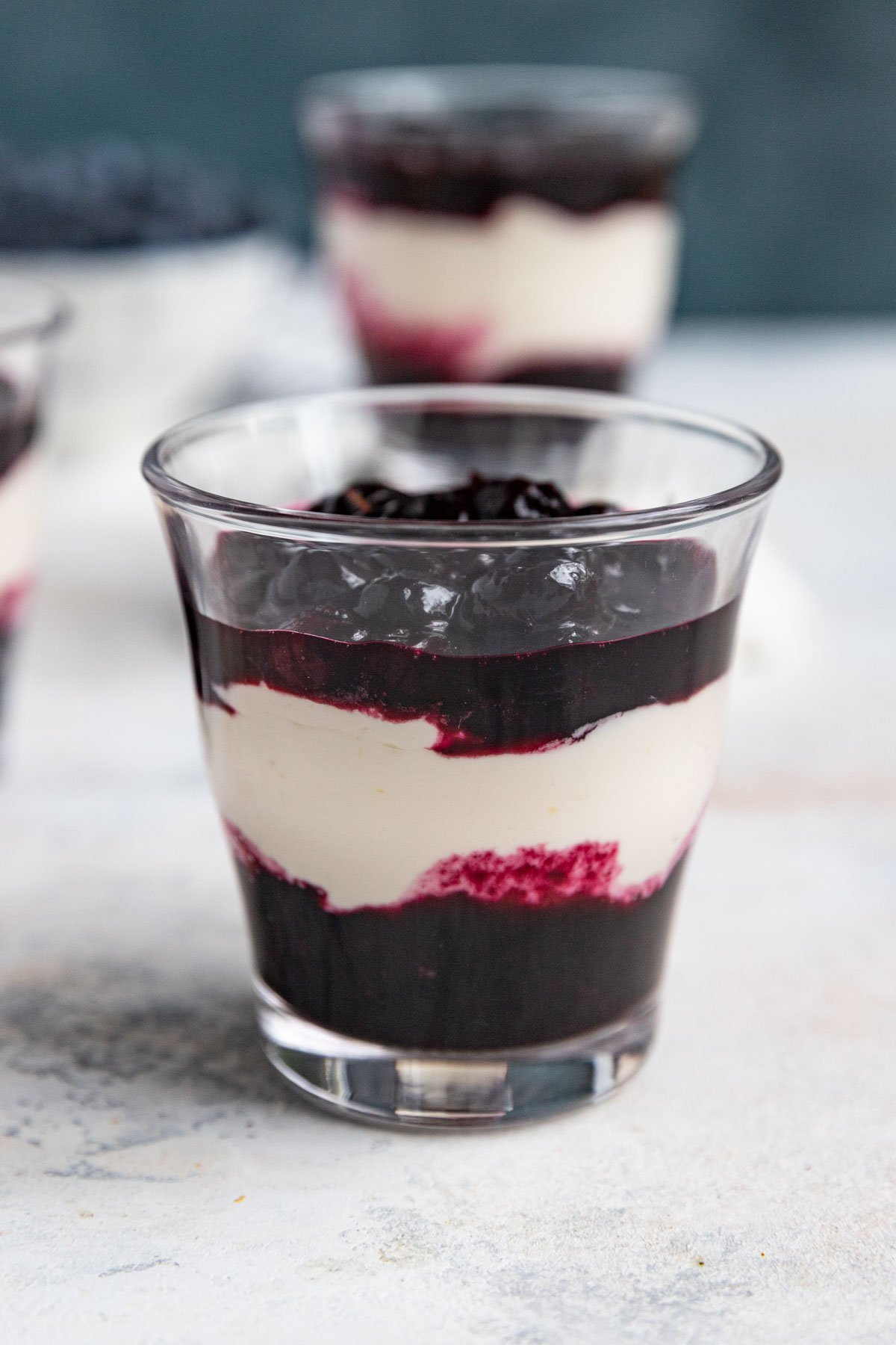 A glass jar with a layer of blueberry compote, then a layer of lemon cream, then another layer of blueberry compote.