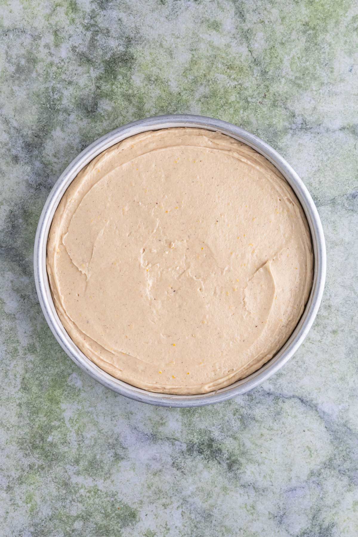 Cake pan with cake batter spread over the blackberries.