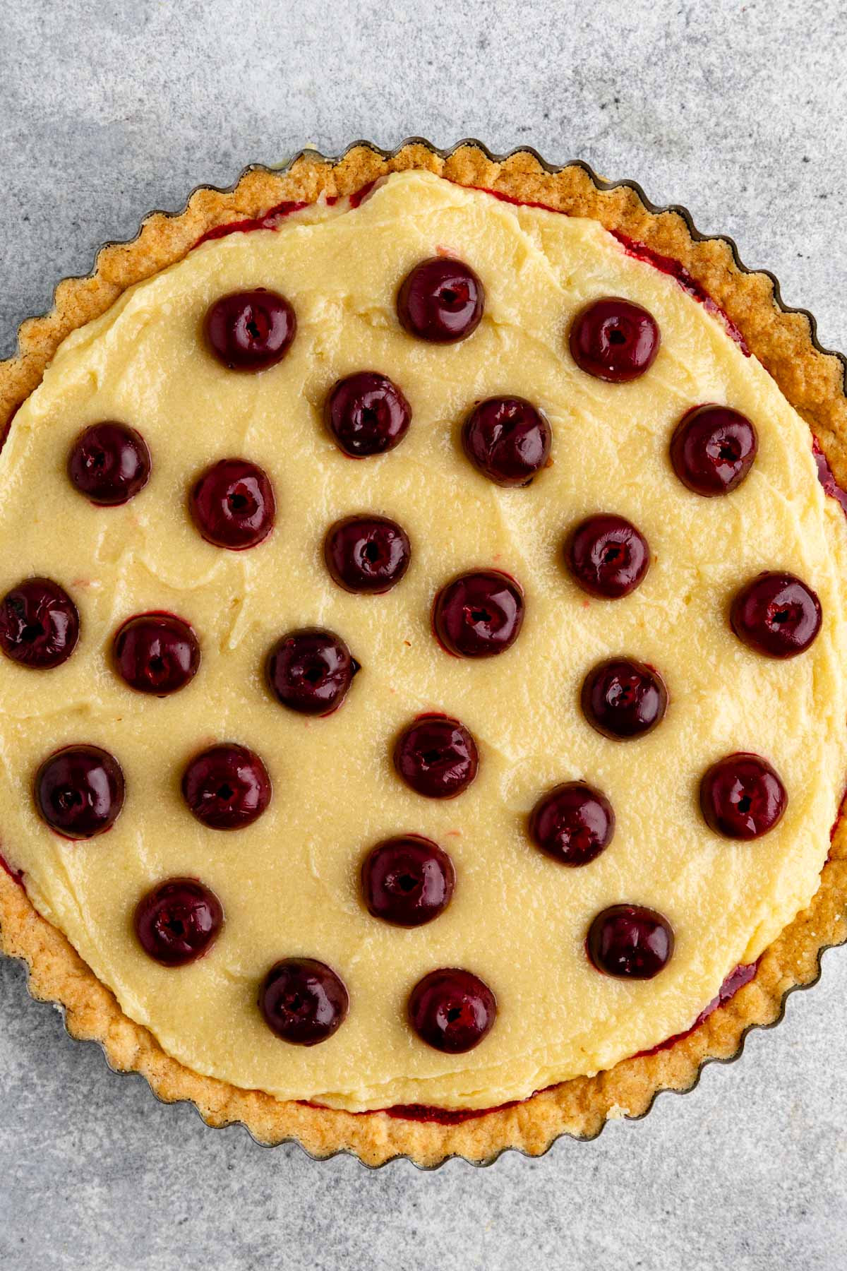 The surface of the frangipane filling with whole pie cherries arranged on top
