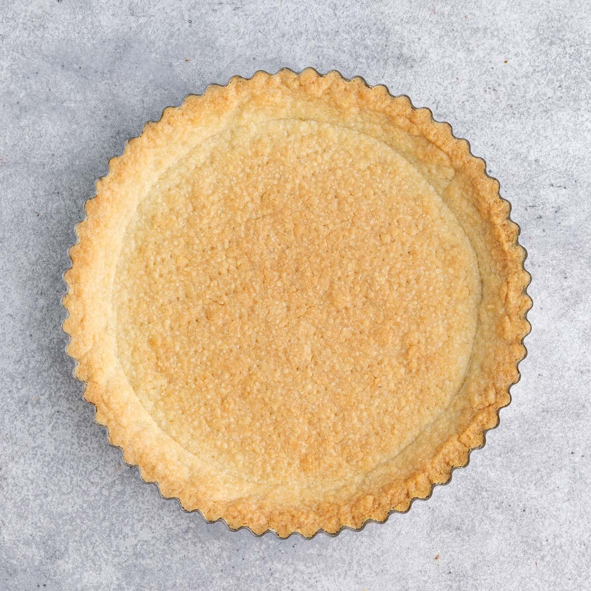 Baked tart in a 9-inch tart pan.  The bottom and tart edges of the tart crust are golden brown
