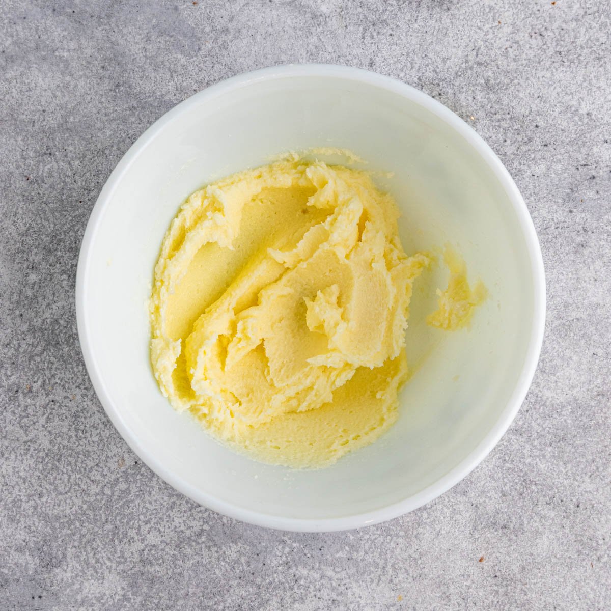 Sugar and butter mixed together in a white ceramic bowl