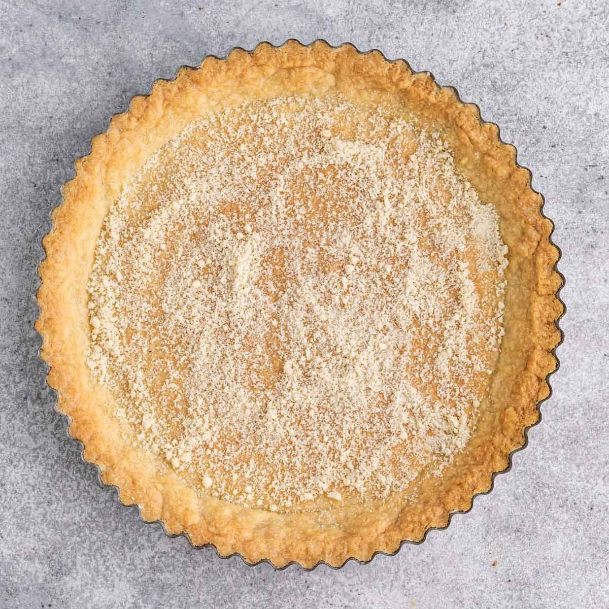Baked tart crust with almond flour spread across the bottom of the crust.