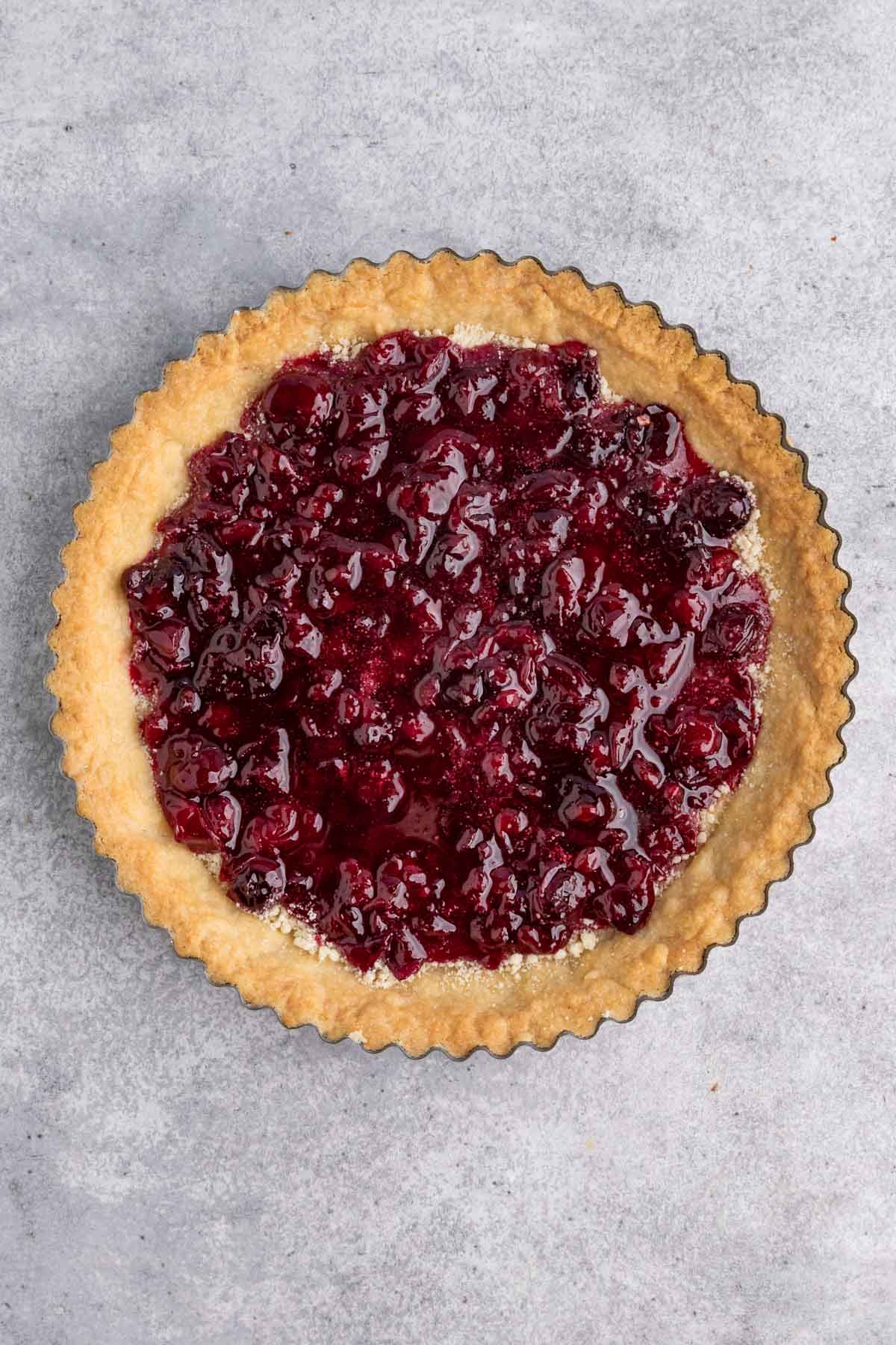 Sour cherry jam spread across the bottom of a prebaked tart shell