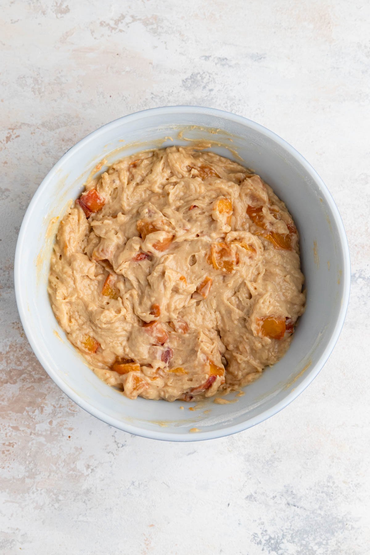 Muffin batter with peaches added to the batter.