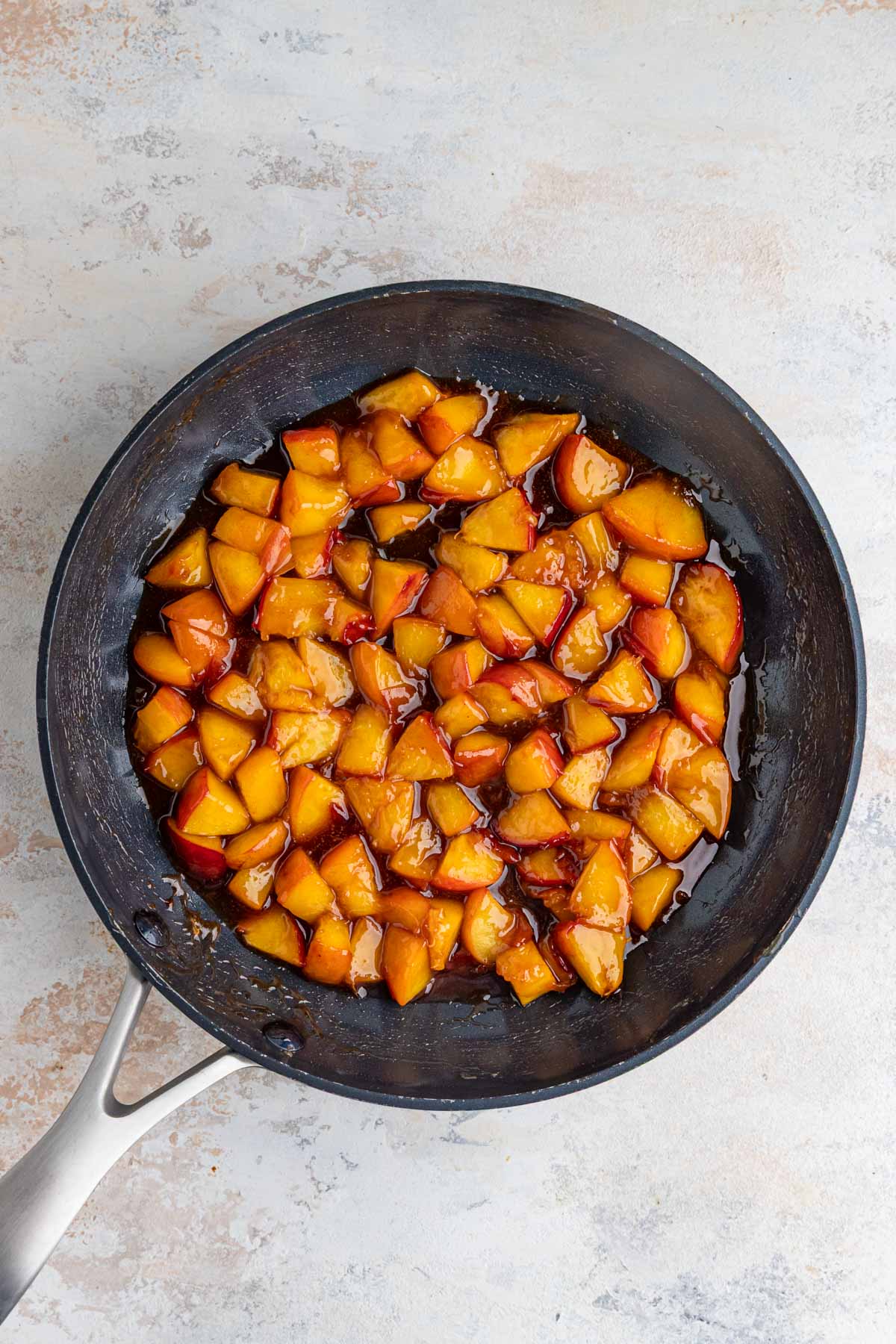 Cooked peaches with butter, sugar, and cinnamon in a non stick pan