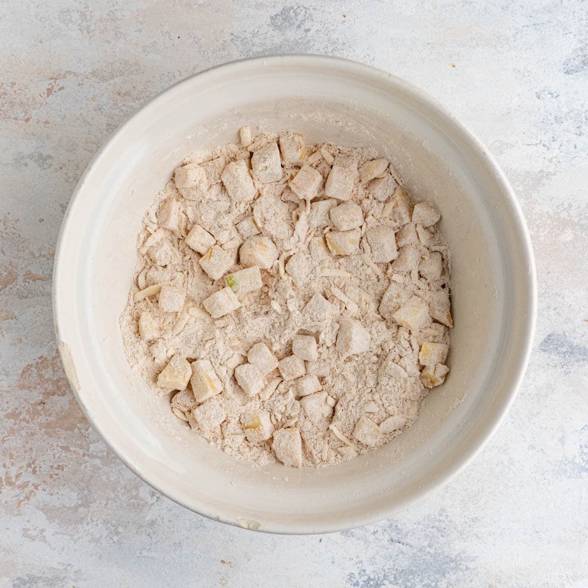 The scone dough with the apples mixed in. The apples are coated with flour.