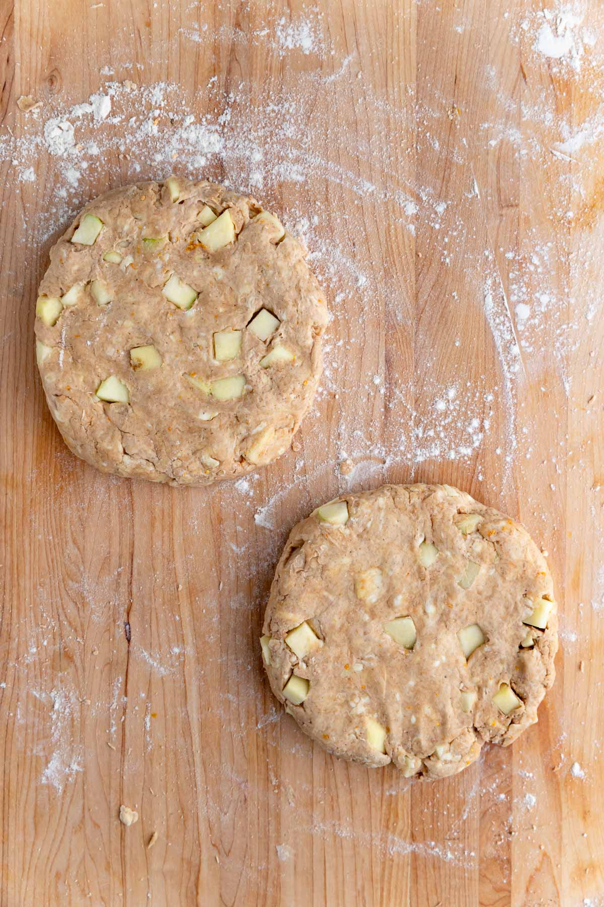 The dough divided and shaped into two 6-inch circles. You can see chunks of apple throughout the dough.