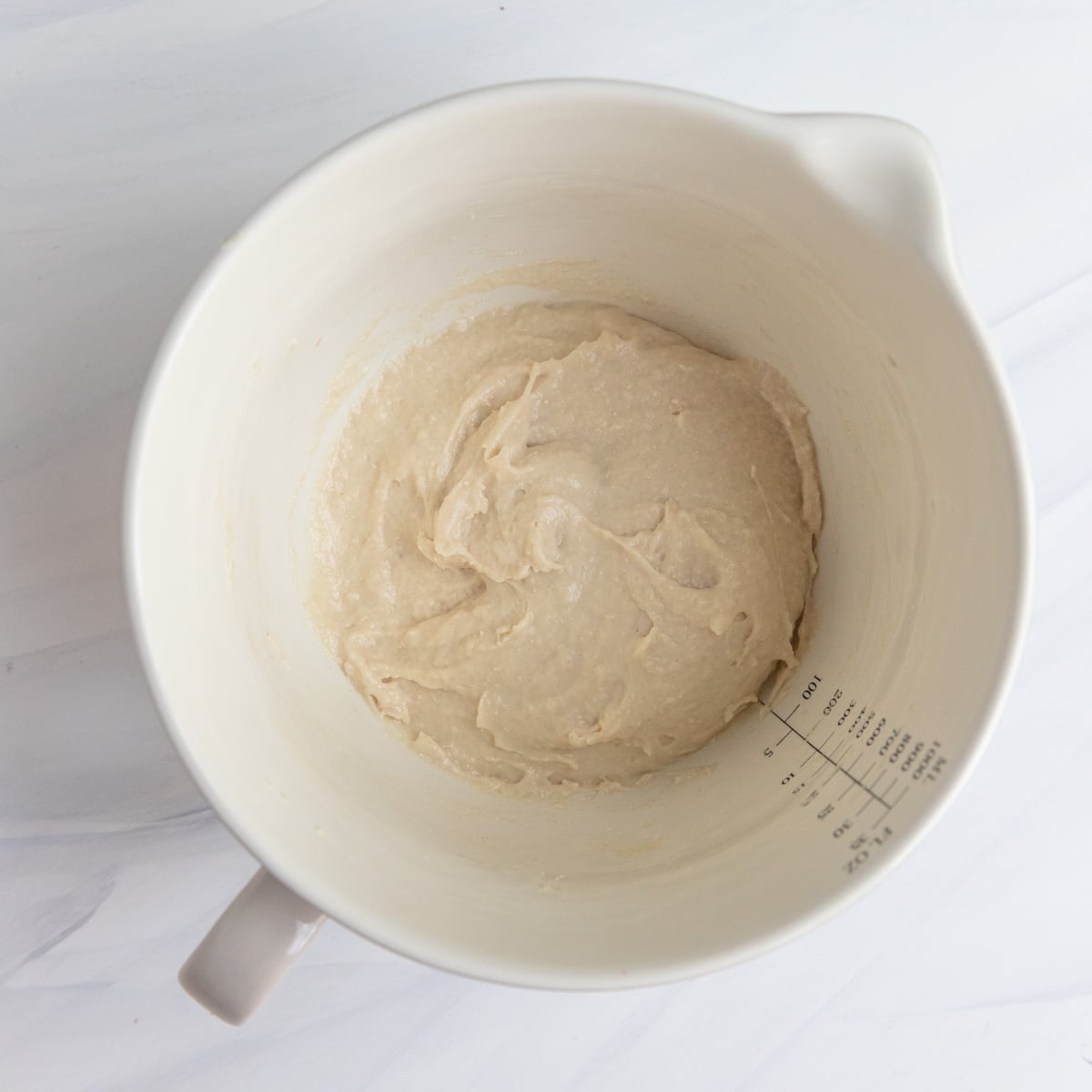 A preferment dough in a small mixing bowl. The dough is made with flour, milk, yeast, and sugar.