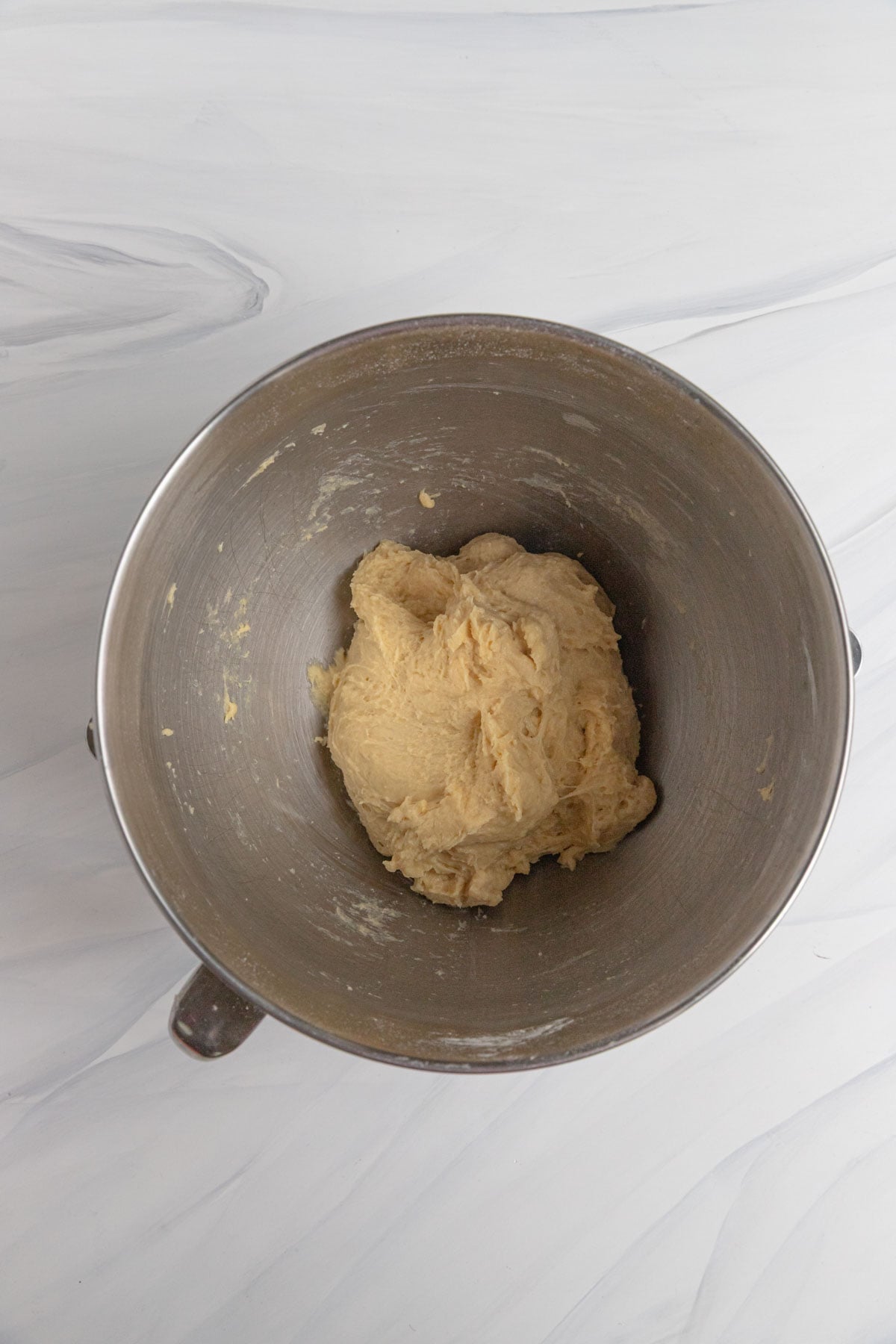 The dough mixed together in a metal mixing bowl. The dough looks shaggy