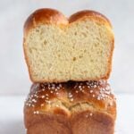 One brioche loaf stacked on top of another loaf. The top loaf has been sliced and you see the crumb of the loaf