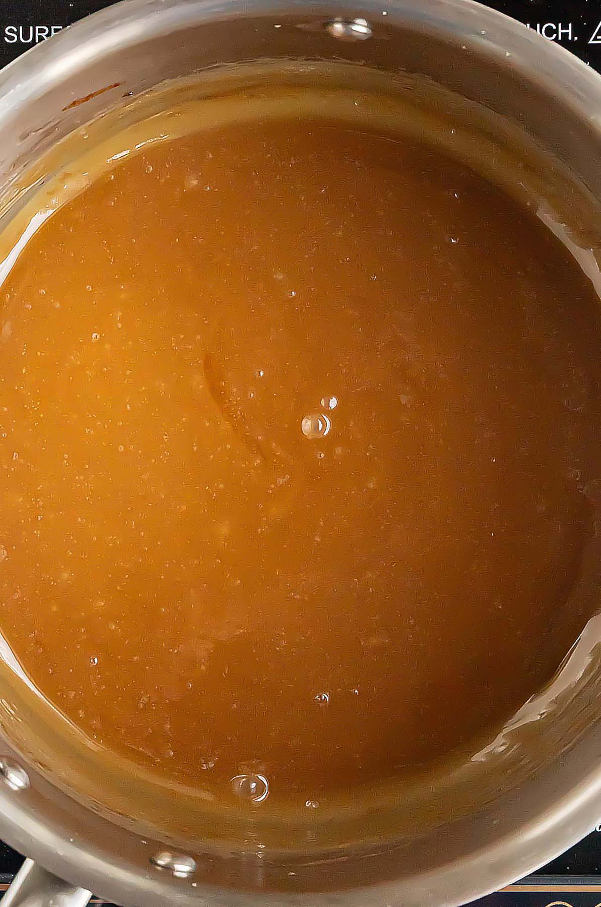 Apple cider caramel sauce in a stainless steel saucepan