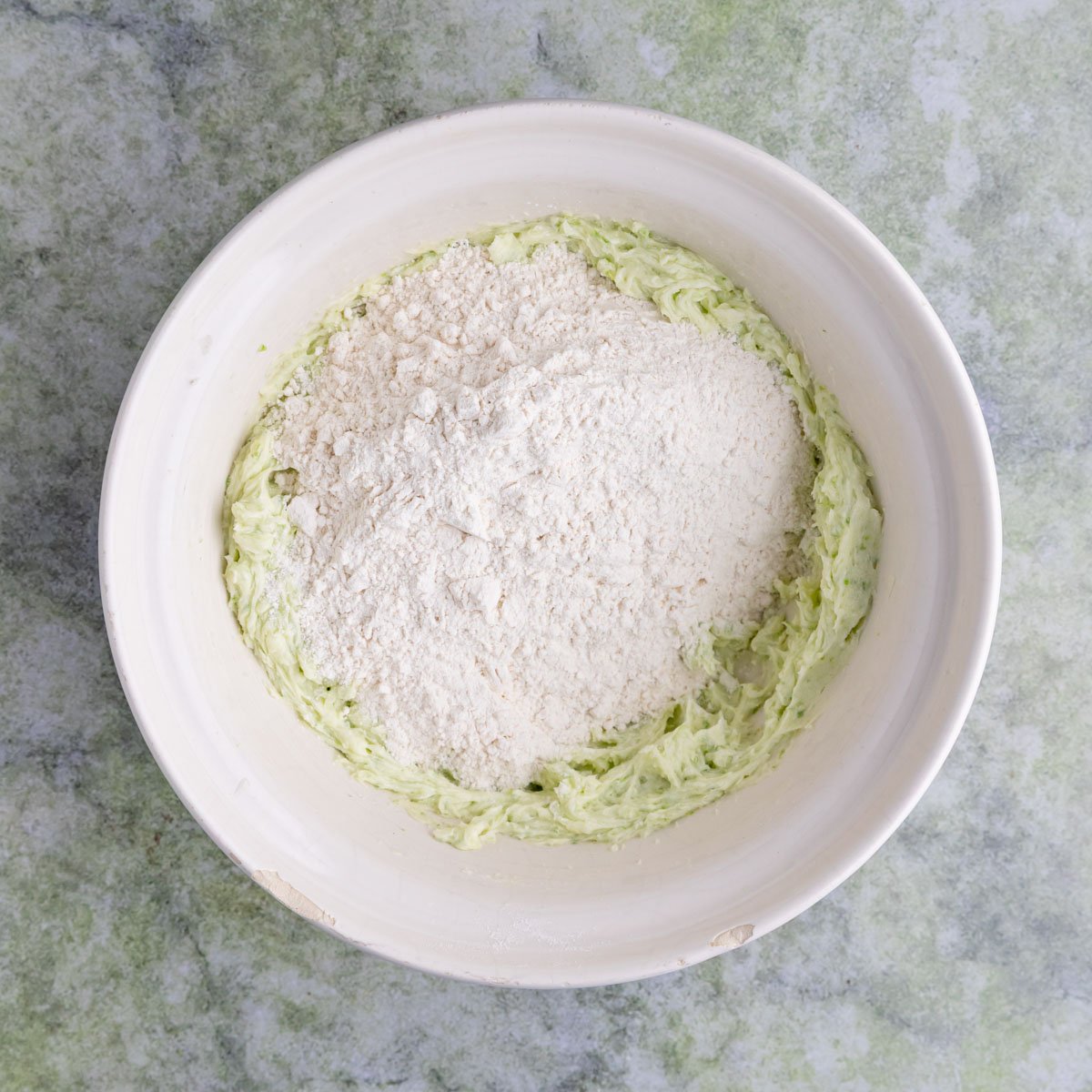 Lime shortbread cookie dough in a large bowl with the flour poured on top