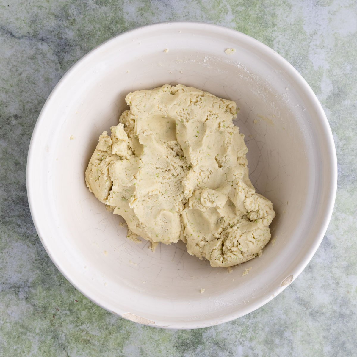 Lime shortbread cookie dough in a large ceramic mixing bowl