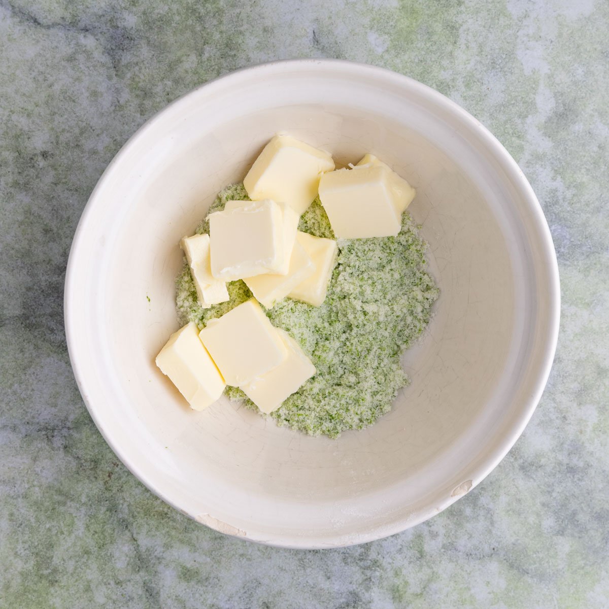 The lime sugar mixture and butter in an off white ceramic mixing bowl