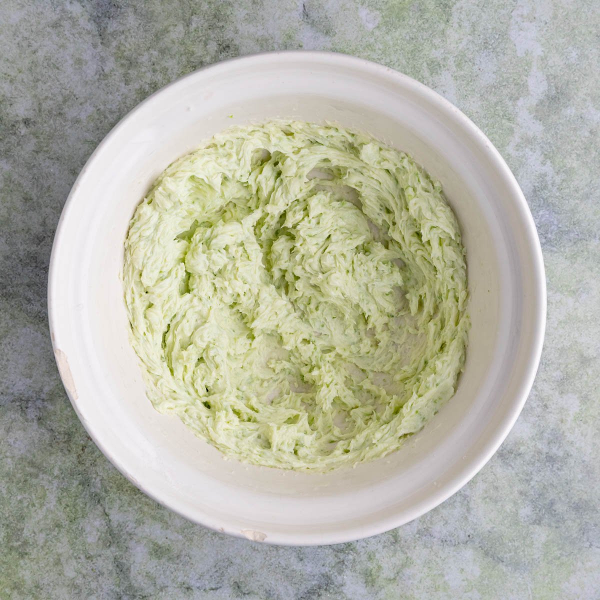 The lime-sugar mixture and butter creamed together in a large ceramic mixing bowl.