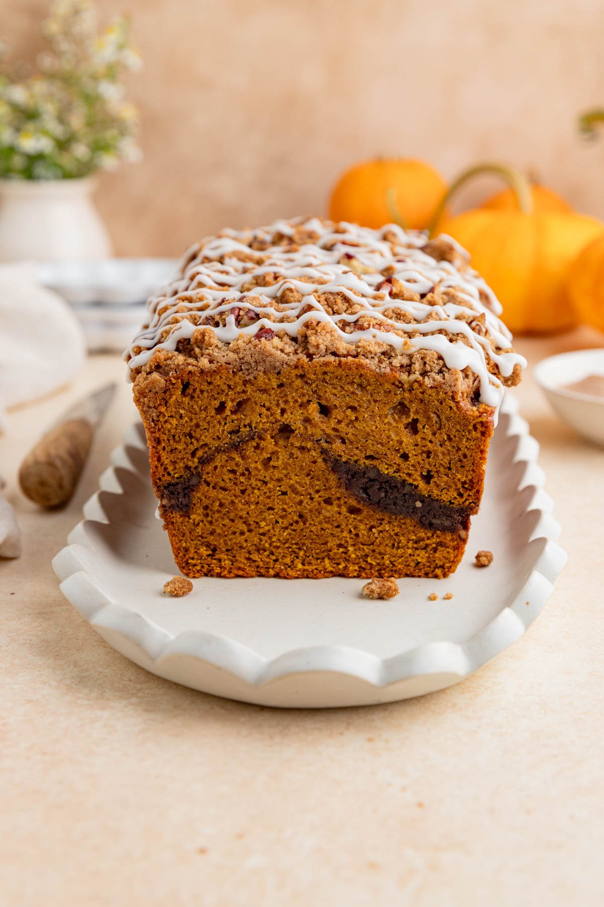 Pumpkin bread with pecan streusel topping. The loaf is cut and you see the sugar cinnamon swirl in the center of the loaf.
