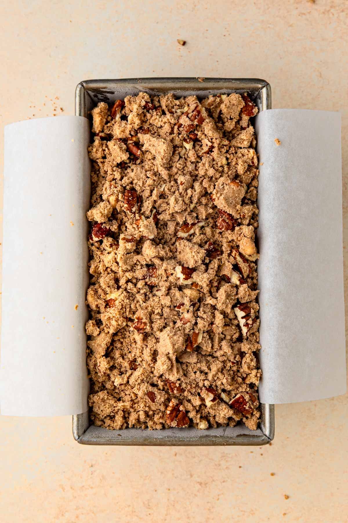 Pumpkin bread batter topped with a pecan streusel in an 8.5x4.5-inch loaf pan.