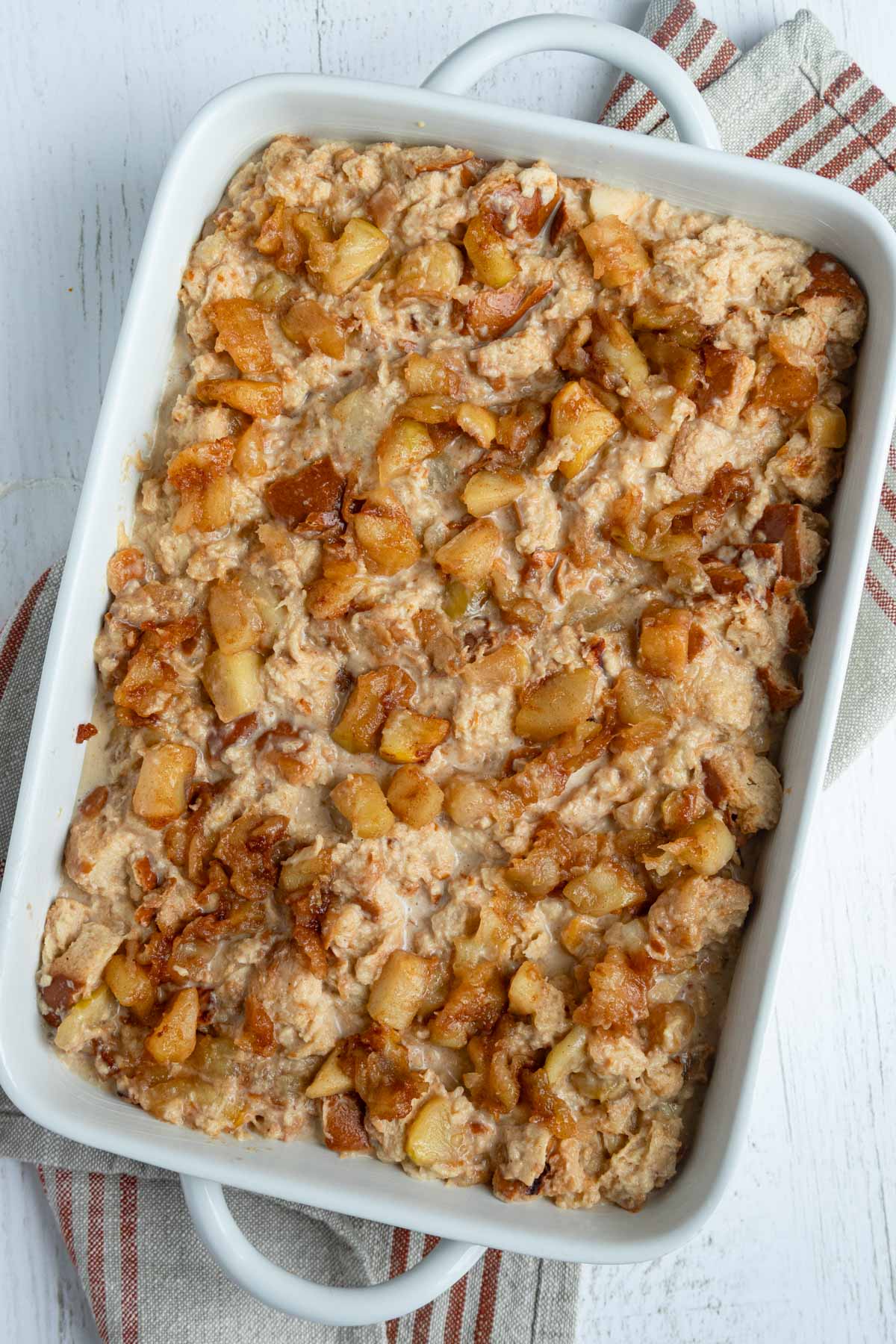Unbaked apple bread pudding in a white rectangular baking dish