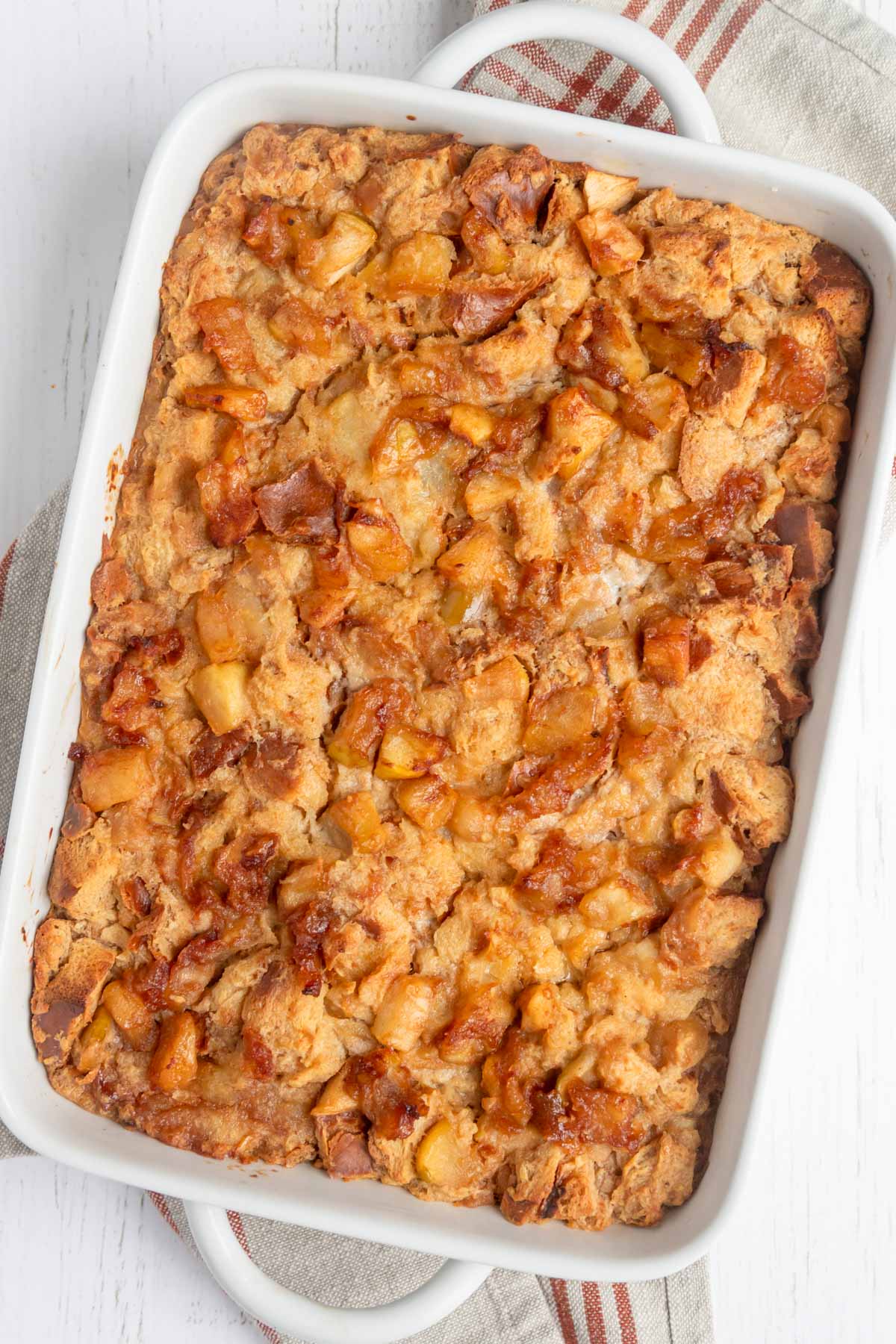 Baked apple bread pudding in a rectangular ceramic white baking dish