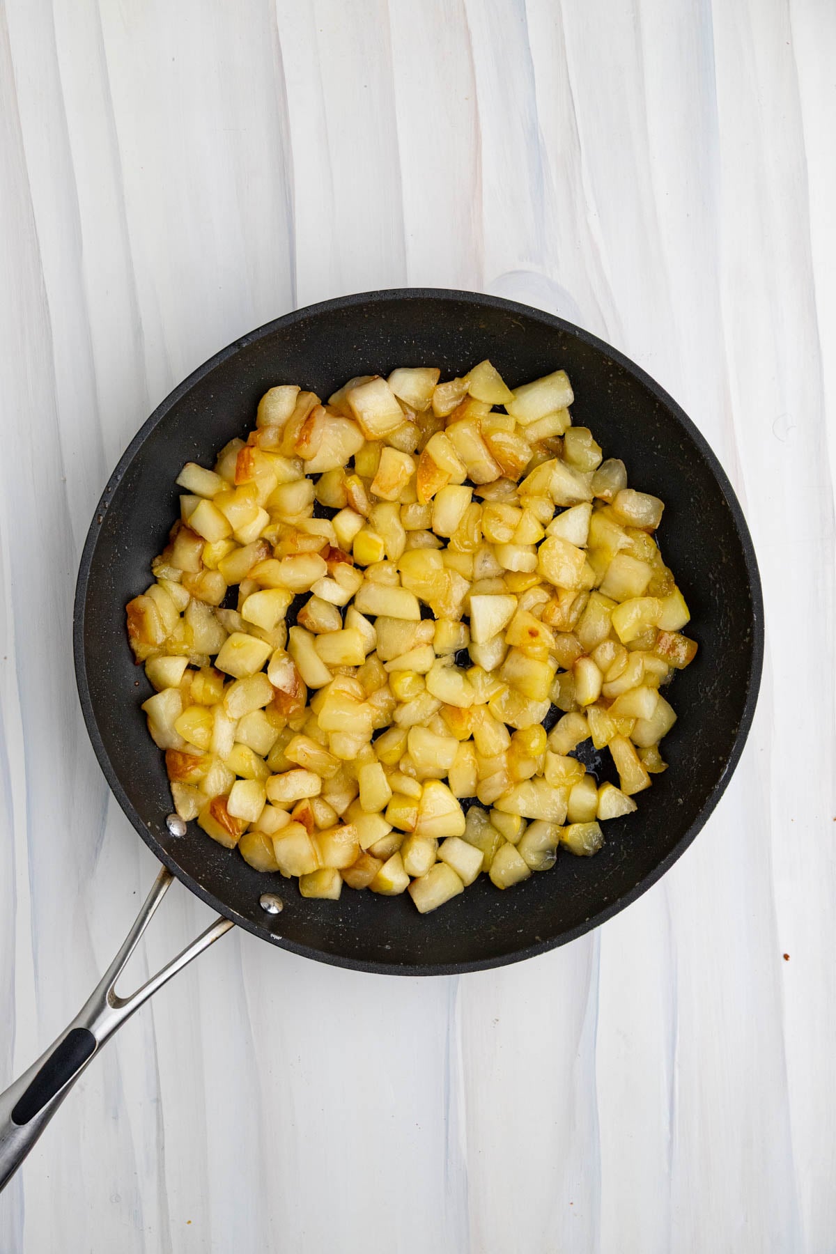 Cooked apples in a nonstick pan. The apples are caramelized and a light brown