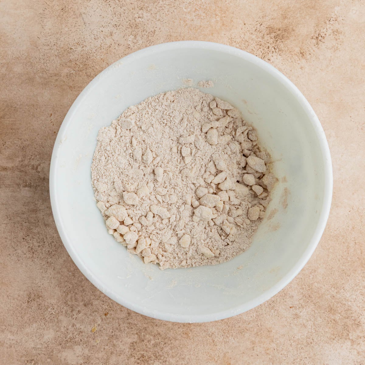 The brown sugar crumble with small pieces of butter in a white ceramic bowl